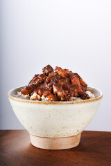 A close-up of a bowl of Taiwanese braised pork rice with a white background and wood grain pattern.