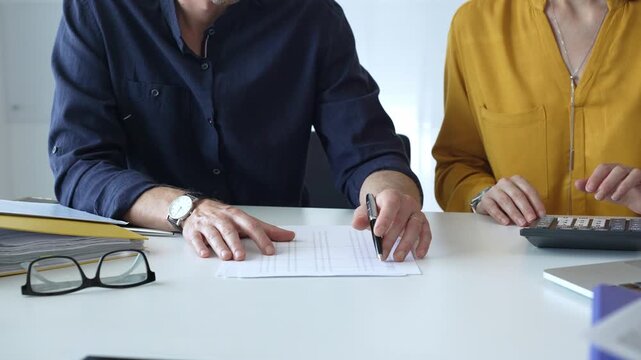 Professional team analyzing contract details, reviewing financial documents, calculating costs at collaborative workplace with laptops and paperwork. Audit and taxes in business