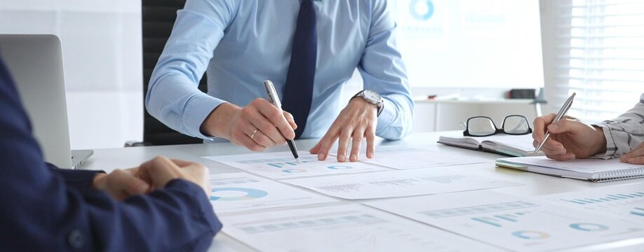 Business professionals study financial charts and graphs during corporate meetings, focusing on data manipulation and market planning