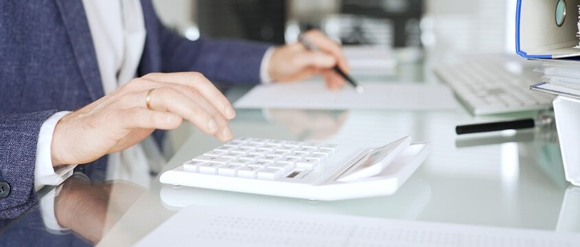 Professional accountant calculating finances and managing paperwork on an office desk, analyzing taxes and budget planning. Audit and taxes in business