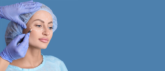 Plastic surgeon marking woman's face on blue background, closeup. Blepharoplasty concept
