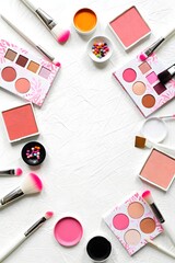 Makeup brushes and palettes arranged on a white textured background for beauty ads