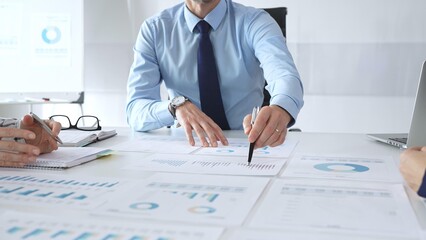 Business professionals study financial charts and graphs during corporate meetings, focusing on data manipulation and market planning