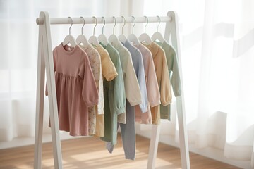 Colorful baby clothes hanging on rack in bright indoor setting second-hand clothing rack