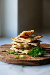 Stack of flatbread with herbs on a wooden board for a delicious appetizer dish recipe