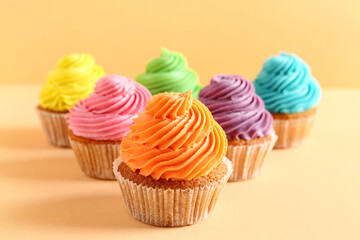 Tasty colorful cupcakes on orange background