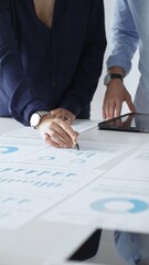 Professional team reviewing financial documents, pointing at charts on desk, collaborating to...