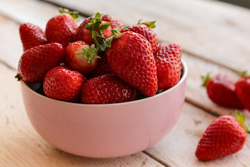 Bowl with fresh strawberries on white wooden table