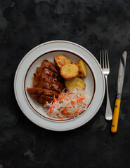 Delicious lunch - grilled turkey, baked potatoes, sauerkraut on a dark background, top view