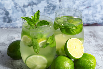 Glasses of cold mojito and lime on blue table