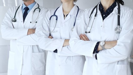 Doctors from a medical team are standing with arms crossed, wearing white coats and stethoscopes, representing unity, success, and trust in a healthcare environment