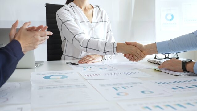 Business handshake agreement in modern office with financial documents, successful partnership deal, teamwork collaboration and corporate negotiation concept
