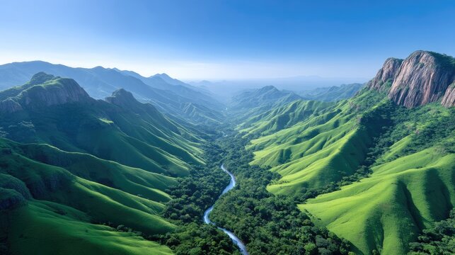 Expansive Aerial View of a Lush Green Canyon River Valley Bathed in Bright Sunlight with Jagged Rocky Outcroppings and a Winding Blue River Below Under a Clear Blue Sky