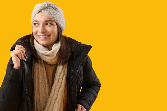 Young woman in winter clothes on yellow background