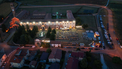 Obraz premium Aerial Night View of a Lively Saint Bernard Festival Event Held at Chiaravalle della Colomba Abbey in Alseno Piacenza Italy With Crowds Enjoying the Festivities Under the Evening Sky