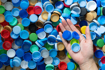 Close up hand holding plastic bottles cap for recycling to conserve the environment, recycling, reuse, garbage disposal, save the world concept