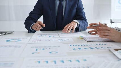 Business professionals discussing financial reports and marketing charts during corporate meeting, focusing on strategy, planning, data analysis, and teamwork