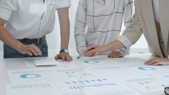 Professional team reviewing financial charts and graphs, working together in modern office space, developing strategic improvements. Business people concept