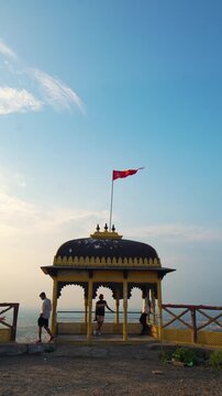 Three hikers trekking during sunset in the mountains under a partly cloudy sky, with a temple creating a breathtaking backdrop at Samai Mata Mandir, Banswara, near Udaipur, Rajasthan, India.