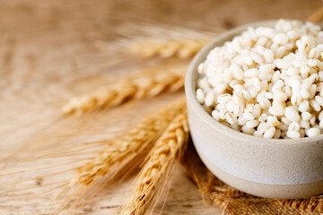 Closeup of cooked barley grains on wooden table.
