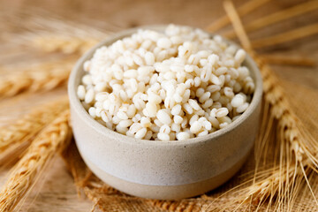 Closeup of cooked barley grains on wooden table.