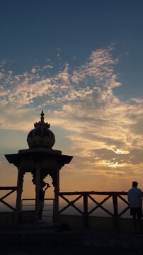 Two hikers trekking during sunset in the mountains under a partly cloudy sky, with a temple creating a breathtaking backdrop at Samai Mata Mandir, Banswara, near Udaipur, Rajasthan, India.