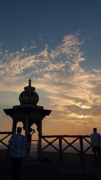 Three hikers trekking during sunset in the mountains under a partly cloudy sky, with a temple creating a breathtaking backdrop at Samai Mata Mandir, Banswara, near Udaipur, Rajasthan, India.
