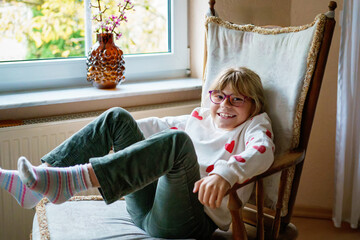 Cozy portrait of smiling elementary school girl with eyeglasses at home