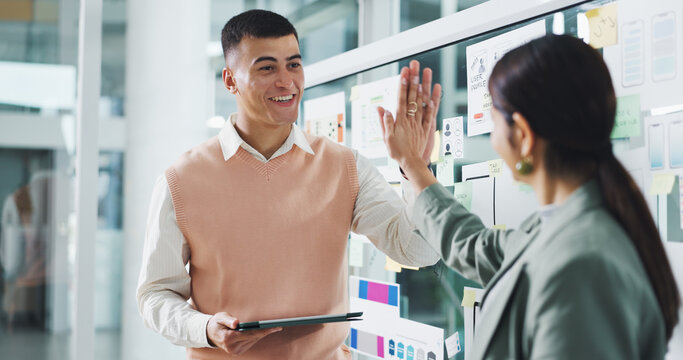 People, high five and team for app development at startup, motivation or tablet for celebration. Woman, man and achievement with goals, success and glass wall with ux design job at digital agency - Powered by Adobe
