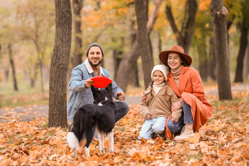 Fototapeta premium Happy family playing frisbee with dog in autumn park