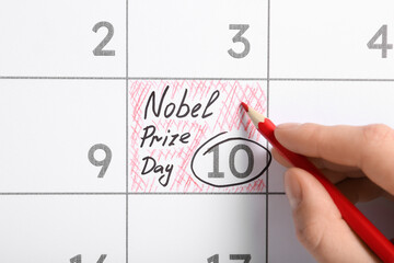 Female hand marking date of Nobel prize day on calendar, closeup