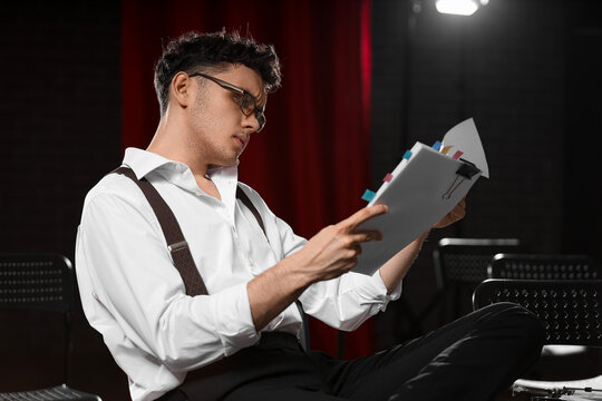 Male screenwriter reading scenario in chair on scene