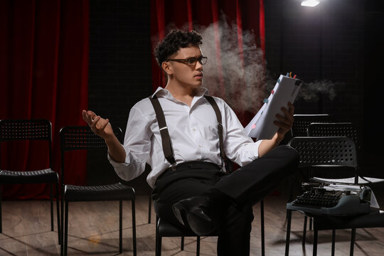 Male screenwriter reading scenario in chair on scene