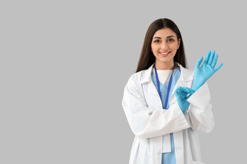 Female doctor with medical gloves on light background. Immunity concept