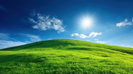 Fototapeta premium Bright Green Hill Under Clear Blue Sky with Sunlight and Wispy Clouds, Ideal for Nature and Landscape Themes in Photography and Design