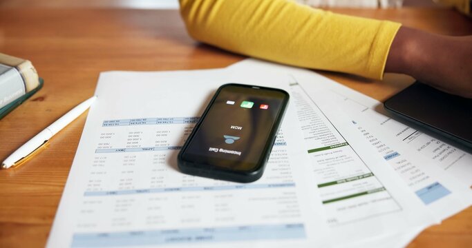Documents, phone screen and ringing with person at desk in home office for accounting or finance. Communication, paperwork and remote work with mobile on table in apartment for call or contact - Powered by Adobe