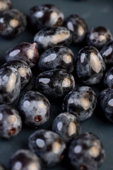 a beautiful ripe grape, torn from a branch, lying on a bowl, covered with drops of water, wet fruits of pure blue grapes on a blue bowl during cooking