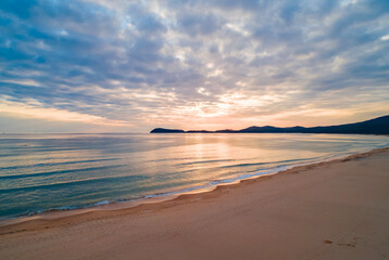 Beautiful coastal sunset with soft waves and serene landscape captured in the evening sky