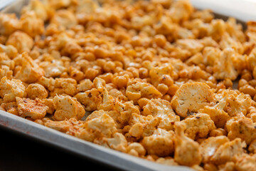 raw cauliflower and chickpeas seasoned with paprika in tray ready to bake