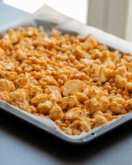 raw cauliflower and chickpeas seasoned with paprika in tray ready to bake