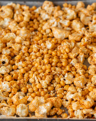 raw cauliflower and chickpeas seasoned with paprika in tray ready to bake