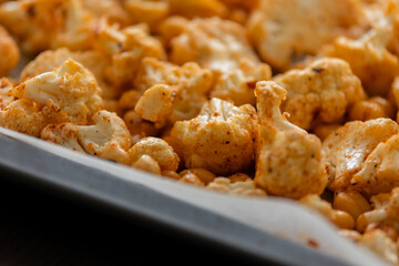raw cauliflower and chickpeas seasoned with paprika in tray ready to bake