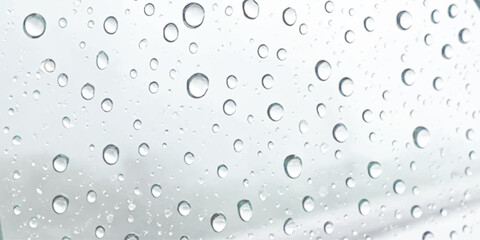 Water droplets on glass surface creating abstract clear liquid texture