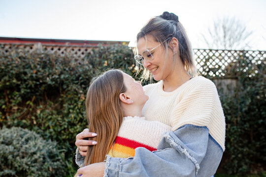 Mother hugging preteen daughter in the garden looking at each other