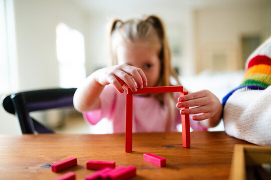 Young girls building colourful rectangular blocks on the table