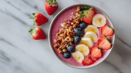 Healthy smoothie bowl with banana, strawberry, blueberry and granola on marble background