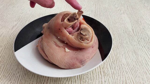 Golden pork knuckle with crispy skin and rich fat layers rests on a pale wood tabletop-warm tones, rustic texture, and savory detail evoke hearty, indulgent comfort