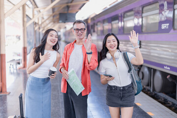 Obraz premium Multi-generational travelers standing on a train station platform, smiling and waving, looking forward to a journey and enjoying their holiday together with excitement