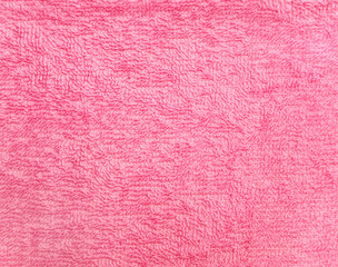 Terry towel or carpet of pink color. Background with fluffy towel terry cloth. Natural cotton fabric texture. Long pile canvas. Close-up of soft cotton terry cloth. Material of domestic cotton rug