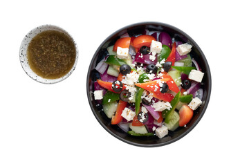 Fresh Greek salad with a side of dressing, showcasing fresh vegetables and feta cheese. The salad is vibrant and inviting
